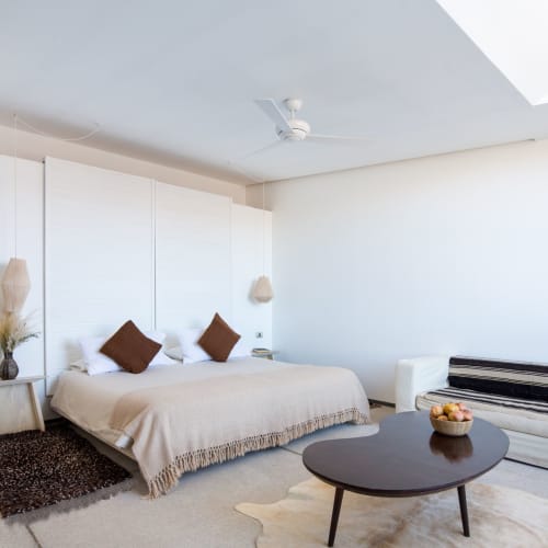 A spacious, bright hotel room with a large bed, white walls, and minimalist decor in Chile.