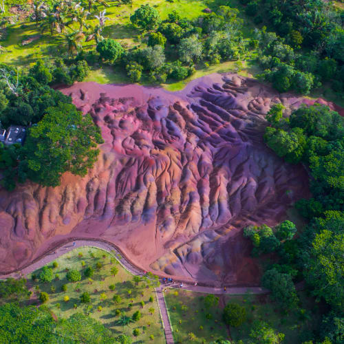 Luftaufnahme eines bunten, geschichteten Vulkanbergs umgeben von üppigem Grün in Mauritius.