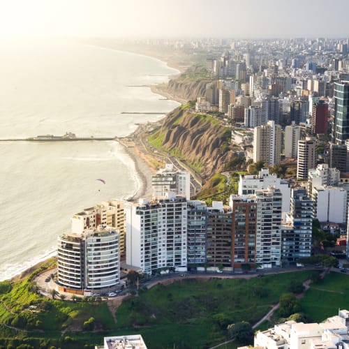 Eine Panoramaaufnahme der Küste und der Stadtszene von Miraflores in Lima, Peru, mit Hochhäusern und Klippen entlang der Küste.