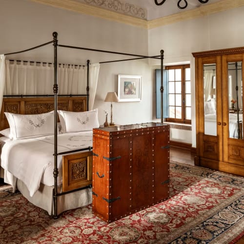Luxurious bedroom with a four-poster bed, wooden furniture, and traditional decor.