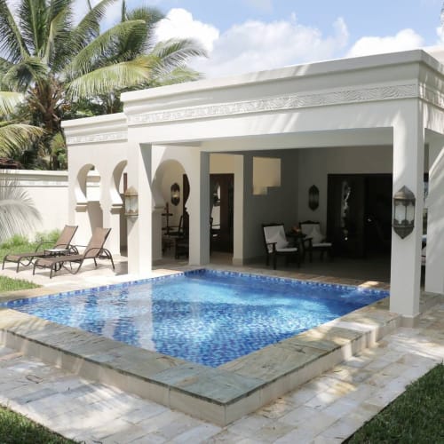 Eine luxuriöse Zweizimmer-Villa mit privatem Pool auf einer tropischen Anlage, mit Outdoor-Lounges und Palmen.