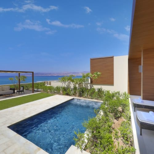 Luxury villa suite terrace with private pool, garden, and sea view at a hotel in Aqaba, Jordan.