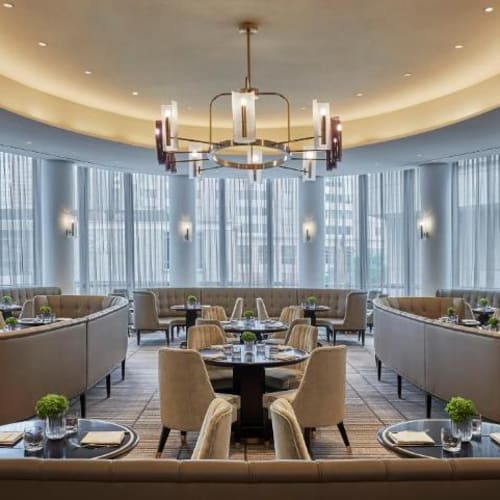 Elegant breakfast restaurant with curved booths, round tables, and large windows in a modern hotel setting.