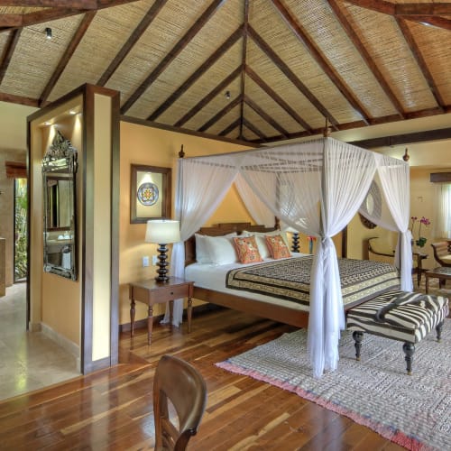 Luxurious bedroom in a villa with a four-poster bed, elegant furniture, and a view of the garden.