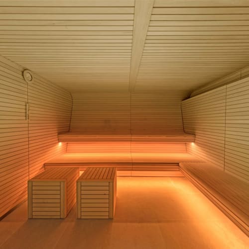 A modern sauna room with wooden benches and warm lighting.