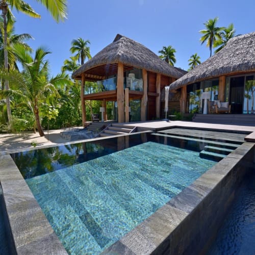 Eine luxuriöse Zwei-Zimmer-Villa mit einem Swimmingpool, umgeben von Palmen in einer tropischen Umgebung.