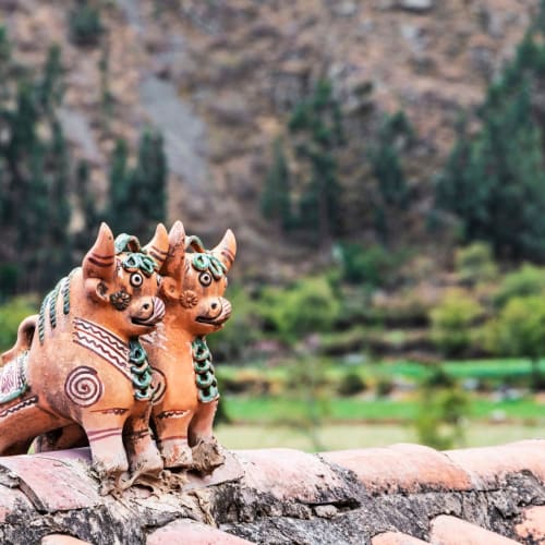 Zwei dekorative keramische Tierfiguren im Pucara-Stil mit bergigem Landschaftshintergrund.