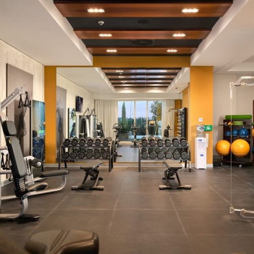 Moderner Fitnessraum mit verschiedenen Trainingsgeräten in einem gut beleuchteten Raum.