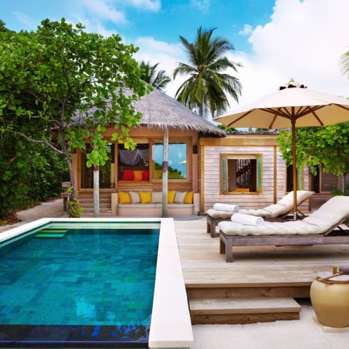 Eine luxuriöse Familienvilla mit privatem Pool, umgeben von üppigem Grün und tropischen Bäumen auf einer tropischen Insel.