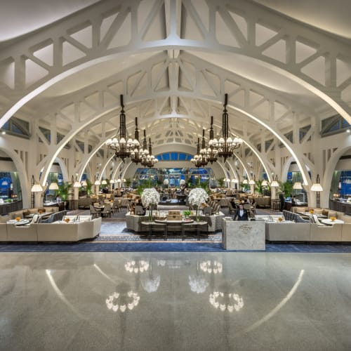 Elegante Hotellobby mit hohen gewölbten Decken, großen Kronleuchtern und stilvollen Sitzbereichen um Blumenarrangements.