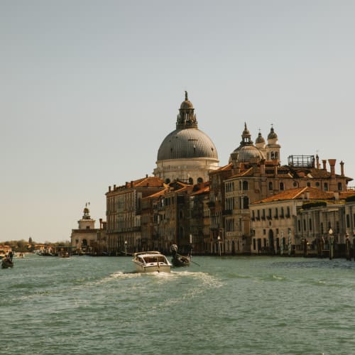 Blick auf Venedig mit historischen Gebäuden entlang eines Kanals, Boote fahren auf dem Wasser.