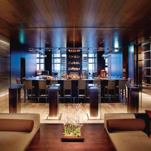 Interior of the Mandarin Bar at Mandarin Oriental Tokyo, with a stylish bar setup, high chairs, and plush seating in a warm, modern atmosphere.