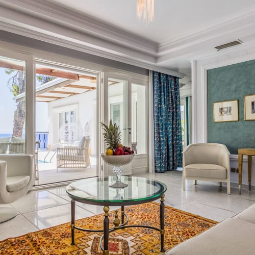 Bright living room with large glass doors leading to an outdoor patio and pool, decorated with modern furniture and a colorful rug.