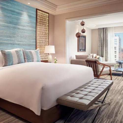 Luxury hotel room with a large bed, sitting area, and a balcony with city view.