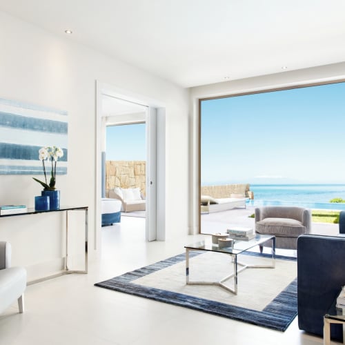 Bright, modern living room with large glass doors revealing a sea view and an outdoor seating area in Halkidiki, Greece.