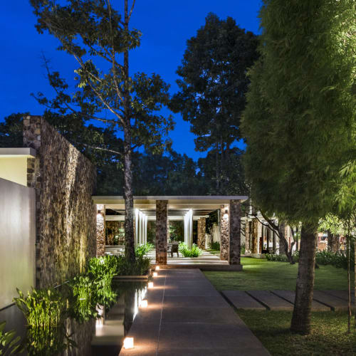 Nachtansicht des Amansara-Restaurants in Siem Reap mit beleuchtetem Weg und üppigem Grün.