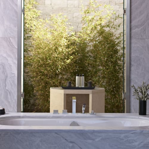 Ein luxuriöses Badezimmer mit eingebauter Badewanne, die zu einem großen Fenster schaut, das auf das grüne Grün im Freien geöffnet wird.