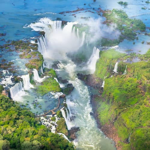 Luftaufnahme der Iguazu-Wasserfälle umgeben von üppiger grüner Landschaft in Brasilien