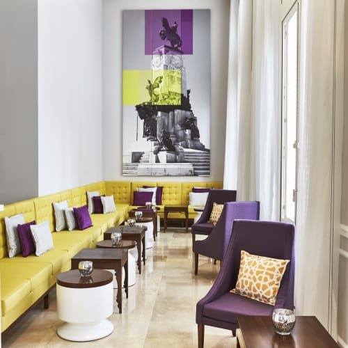 Eleganter Hotel-Lobby mit gelbem und violettem Sitzbereich und moderner Wanddekoration.