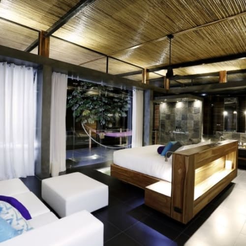 Luxuriöses Hotzzimmer mit modernen Möbeln, großen Fenstern mit weißen Vorhängen und Blick auf eine Außenterrasse im Kura Boutique Hotel in Uvita, Costa Rica.
