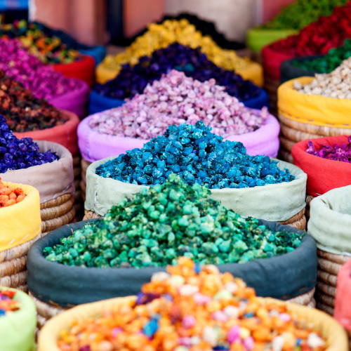 Colorful bags of dried flowers or spices arranged in a market stall.