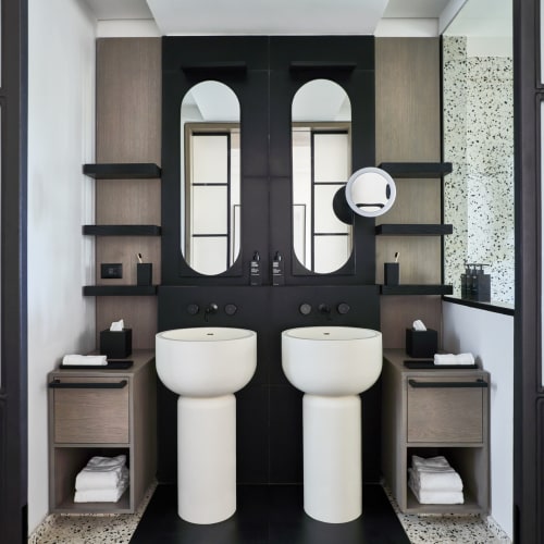 Ein modernes Badezimmer mit zwei Waschbecken, passenden Spiegeln und symmetrischen Regalen auf jeder Seite.