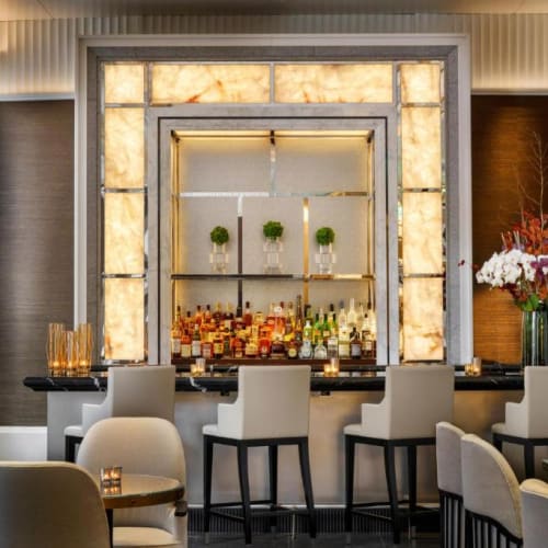 Elegante Hotelbar mit hintergrundbeleuchteter Dekowand und einer Vielzahl von Spirituosenflaschen.