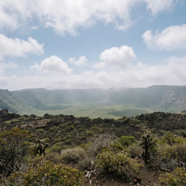 Weitwinkelansicht des Kraterrandes des Vulkans Sierra Negra mit spärlicher Vegetation unter bewölktem Himmel auf den Galapagos-Inseln.