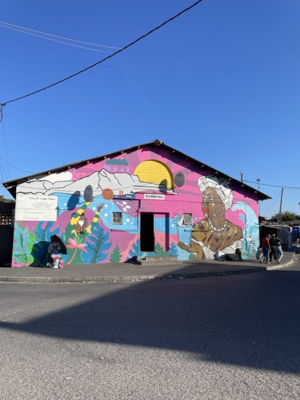Colorful mural on a building in Cape Town with vibrant images of a woman holding a cocktail and playful abstract elements.