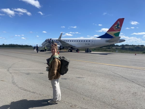 A woman standing on the tarmac with a South African Airways plane in the background.