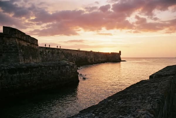 Spaziergänger auf Cartagenas 11 Kilometer langer historischer Stadtmauer bei Sonnenuntergang über dem Karibischen Meer