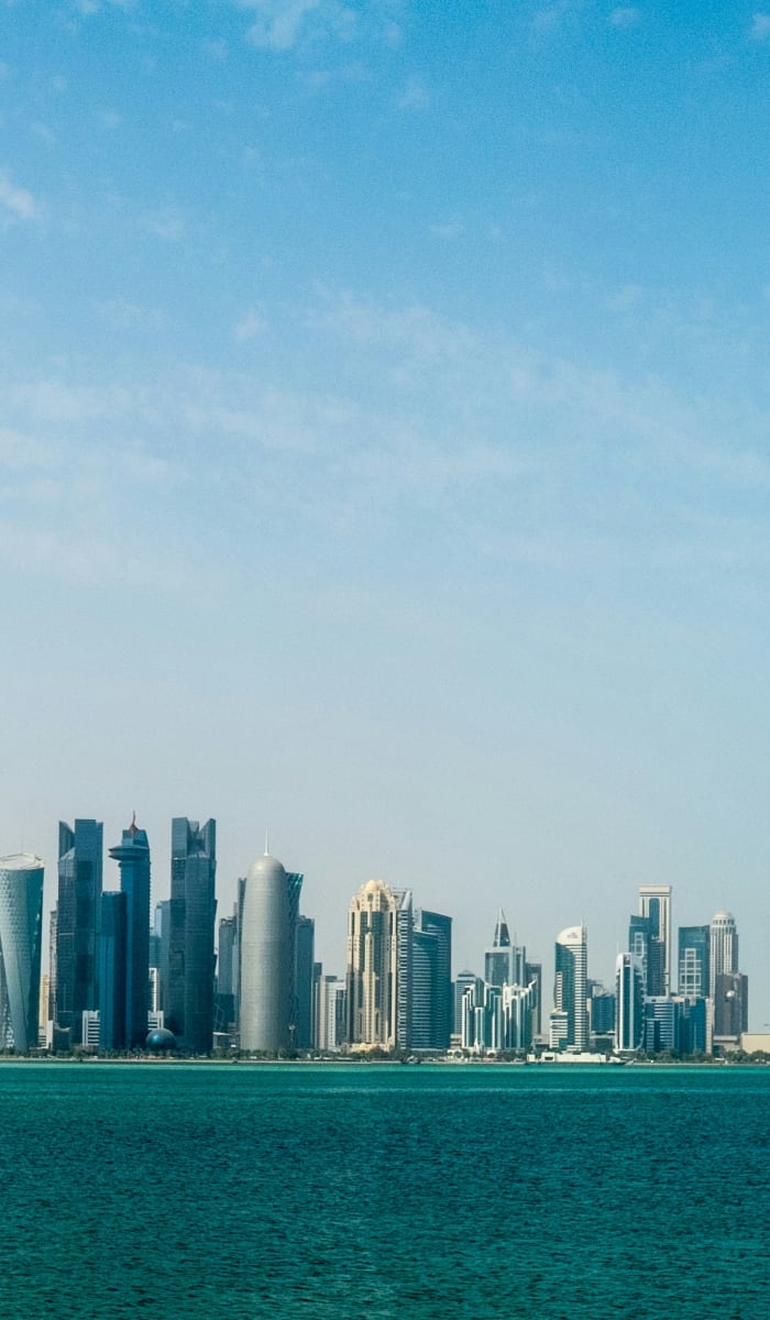A wide view of Doha's skyline across a body of water on a clear day.