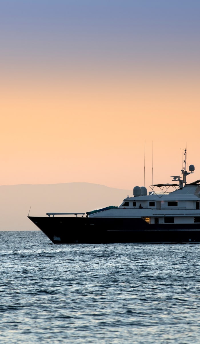 Luxury yacht sailing on the calm ocean near the Galapagos Islands during sunset.