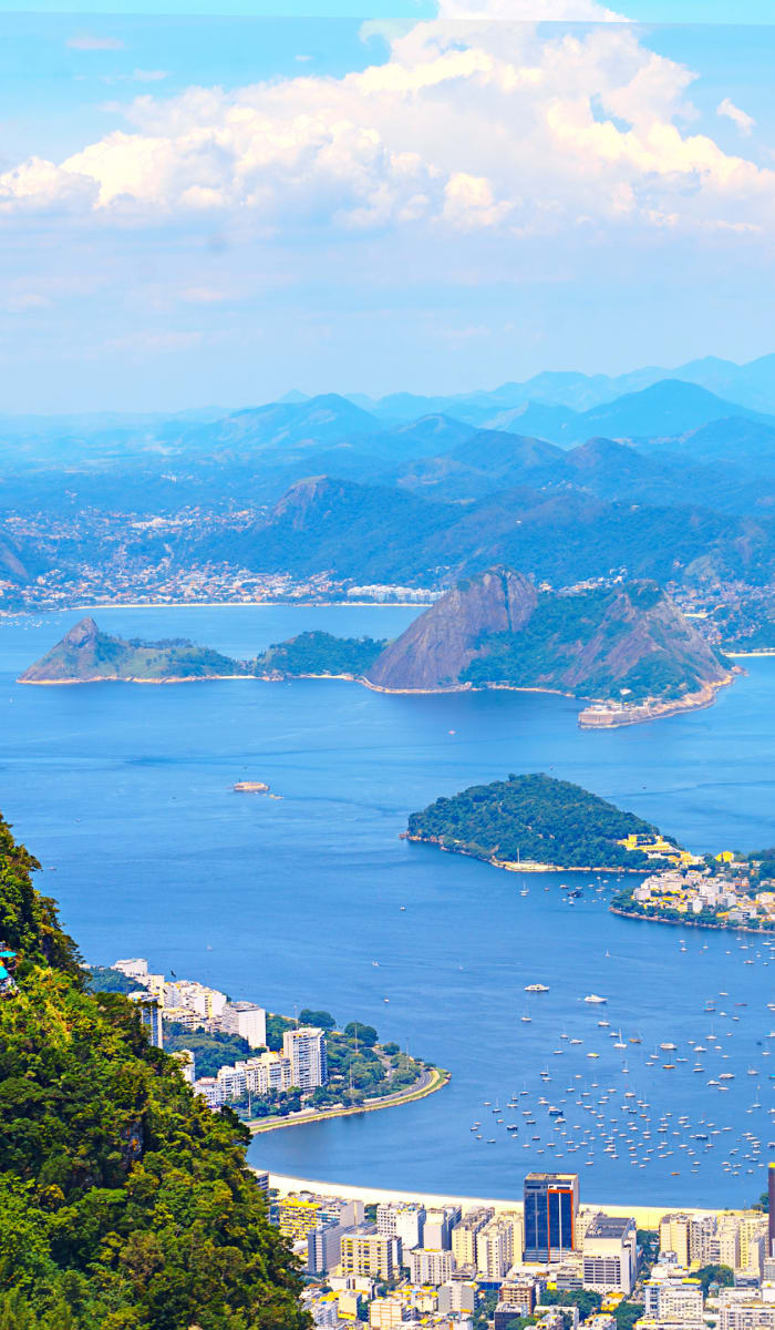 A panoramic view of Rio de Janeiro featuring the Christ the Redeemer statue on Corcovado Mountain overlooking the city and bay.