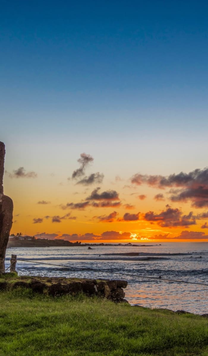 Moai statue on Easter Island with a sunset over the ocean in Hanga Roa.