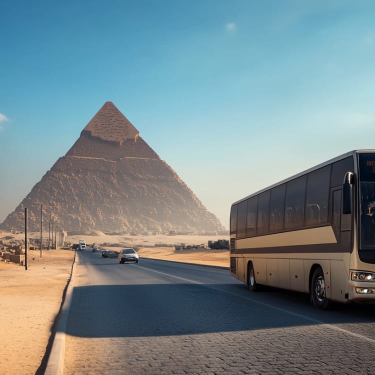 Ein Reisebus fährt auf einer Straße mit Pyramiden im Hintergrund in Ägypten.