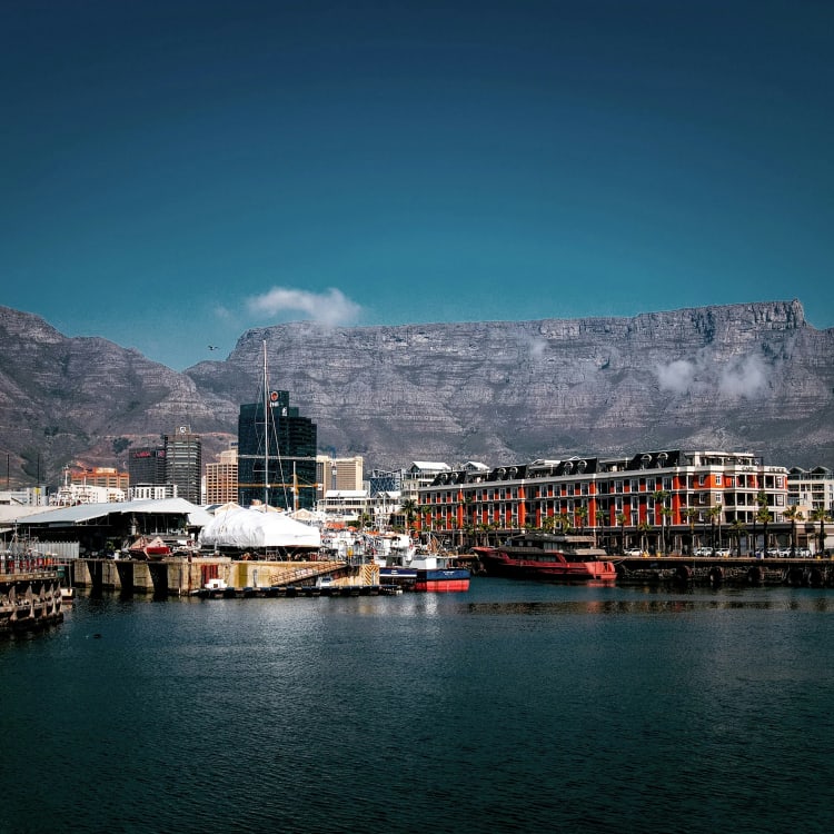 View of V&A Waterfront in Cape Town with mountains in the background and boats in the harbor.