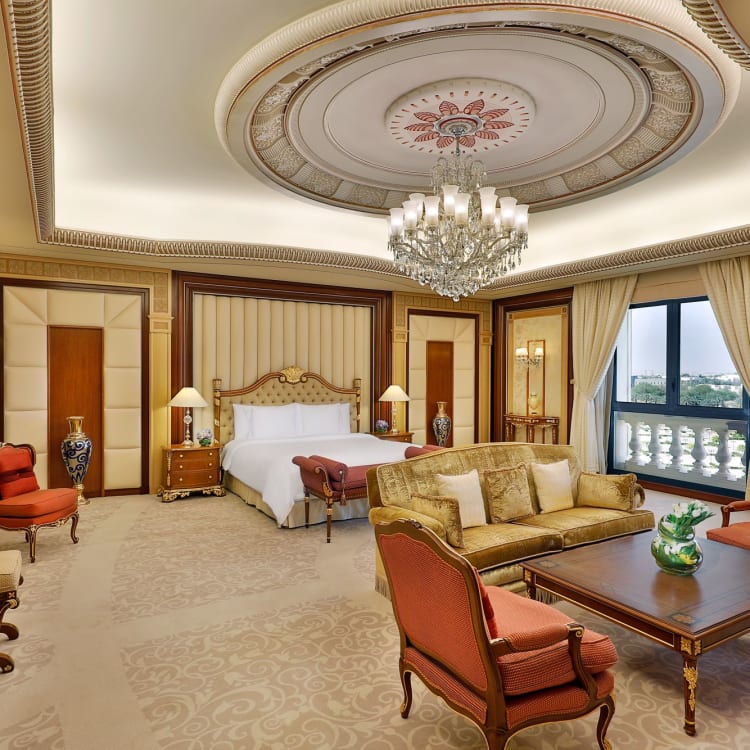 Ein großes Schlafzimmer eines Hotels mit einer Sitzecke vor einem Kingsize-Bett und einem Kronleuchter
