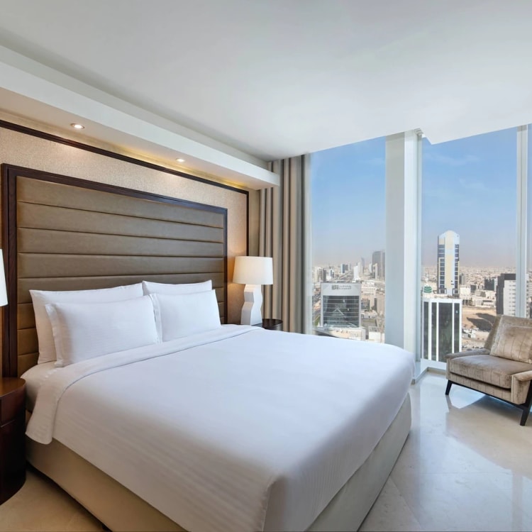 A hotel room with a king size bed overlooking the city