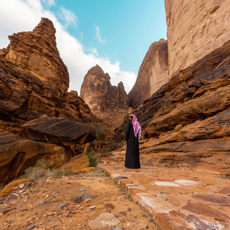 A man infront of the Jabal Ikmah mountain in Alula
