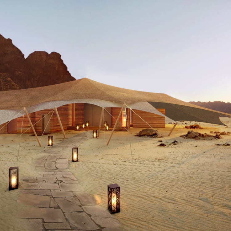 A tend in the desert with a lighted path leading towards it and the mountains in the back