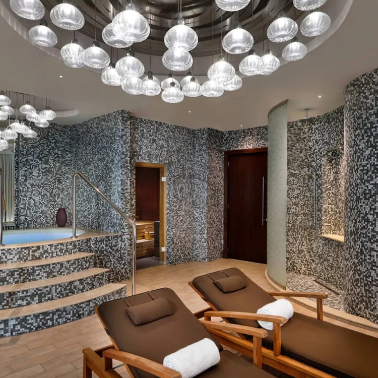 The spa area of a hotel with 2 lounge chairs and a whirlpool in the back