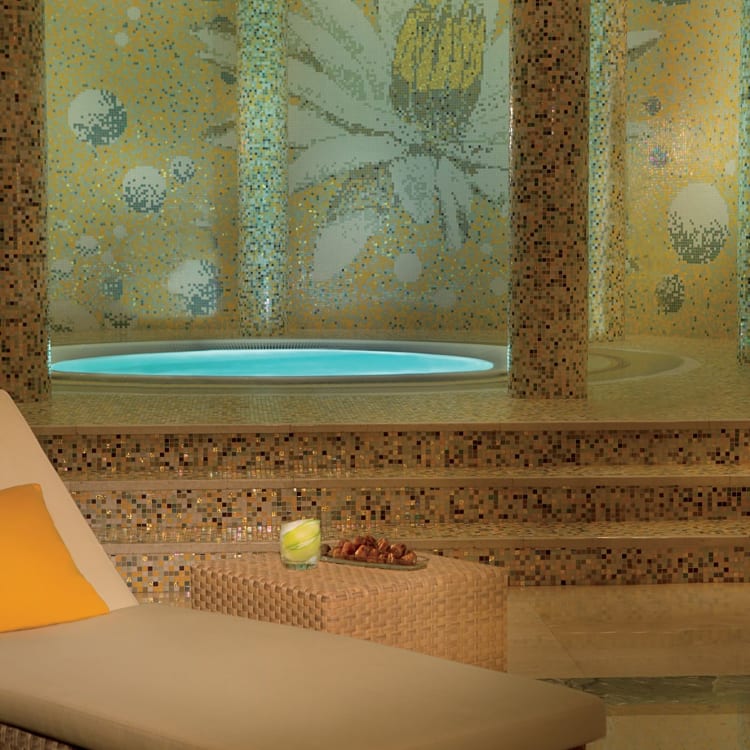 The spa of a hotel with a whirlpool in the back and a lounge chair in front