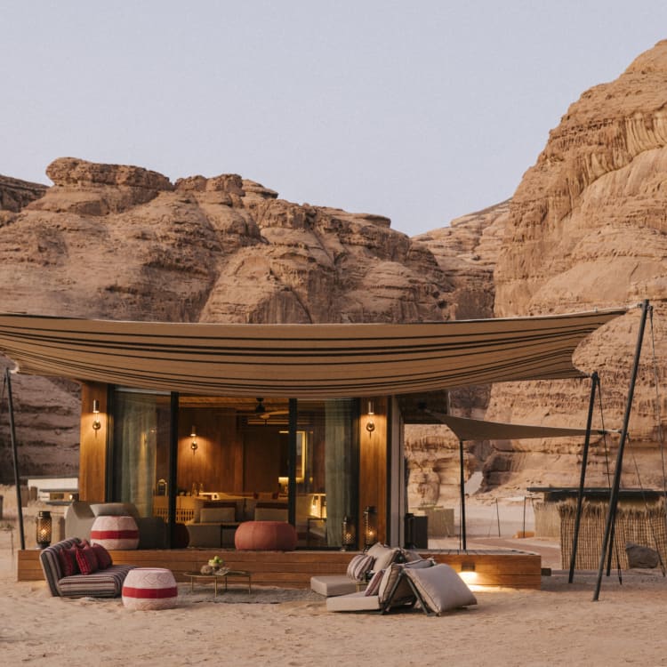 A outside view of a hotel room in the shape of a tent in front of rock formations