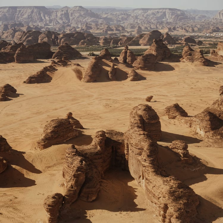 Eine Wüstenlandschaft mit zahlreichen großen Felsformationen und Formationen, die an architektonische Strukturen erinnern, in Al-Ula.