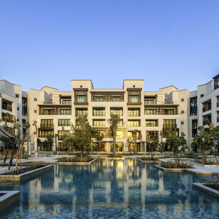 Ein luxuriöser Wohnkomplex mit einem zentralen Pool und üppiger Vegetation in Dubai.