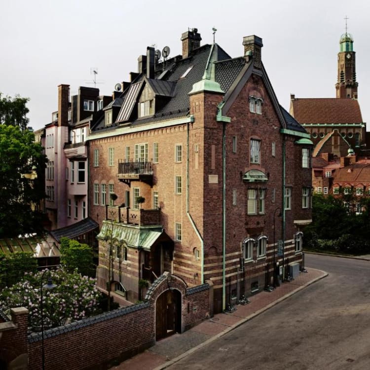 Historic brick building with decorative architectural features on a quiet street in Stockholm.