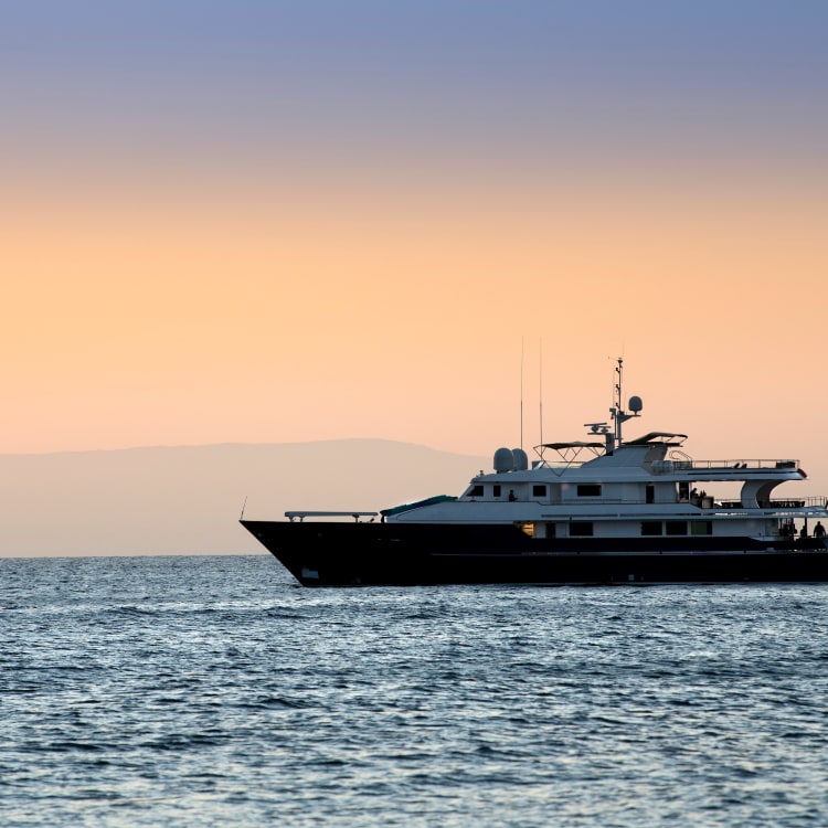 Luxusyacht, die bei Sonnenuntergang auf dem ruhigen Ozean vor den Galápagos-Inseln fährt.