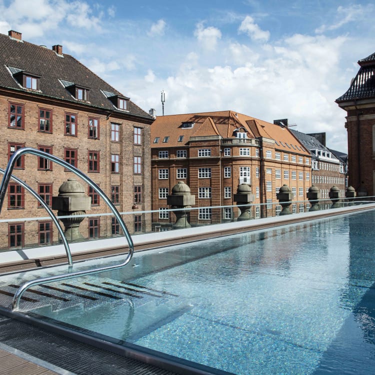Ein Dachpool mit Blick auf historische Backsteingebäude an einem sonnigen Tag.