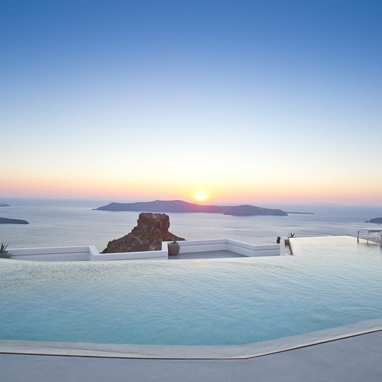 Infinity-Pool mit Blick auf den Ozean bei Sonnenuntergang auf Santorini.